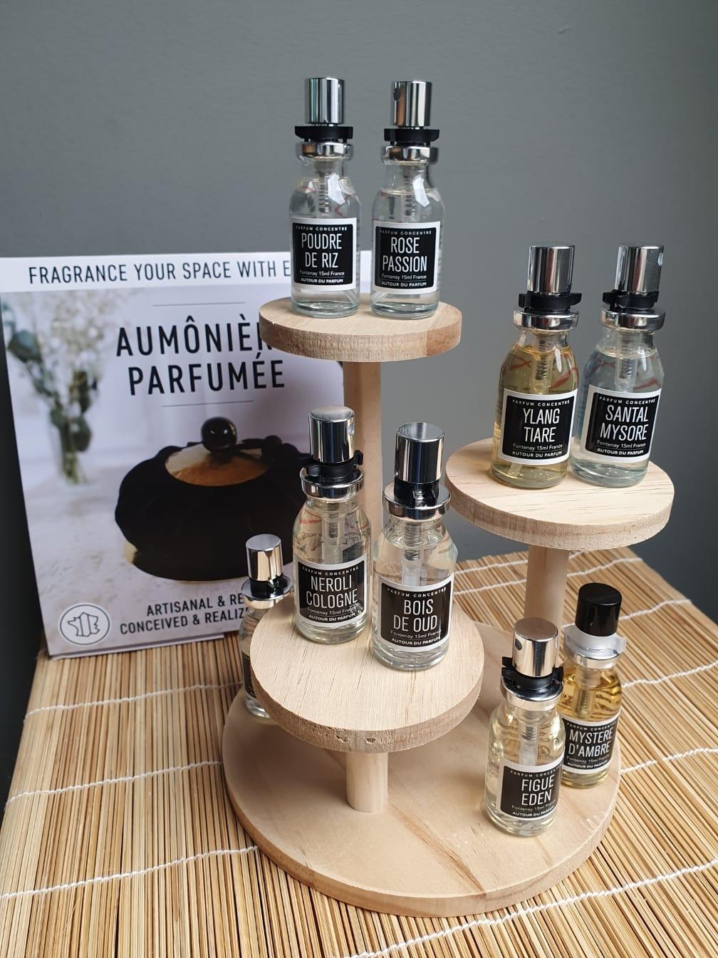 Différents parfums de la marque autour du parfum , posés sur une étagère en bois 
