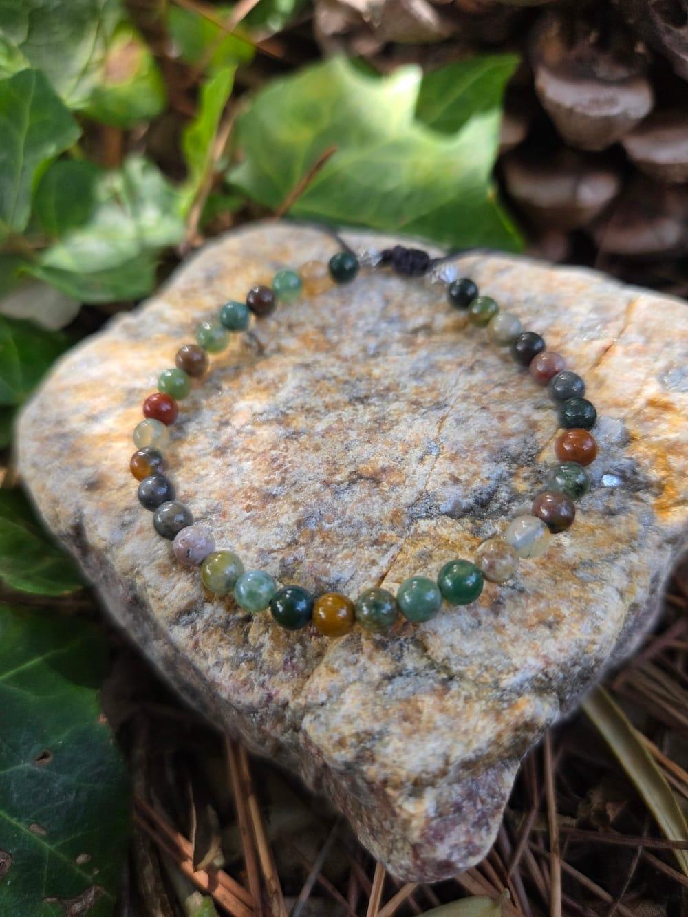 un bracelet de perles en pierres naturelles posé sur une pierre de granit au milieu de la nature  