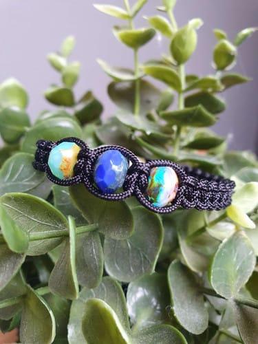Bracelet noir avec des pierres multicolores sur fond de verdure.D'Ici et de Claire