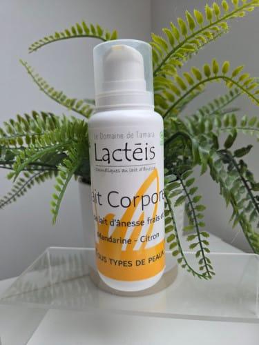 un flacon de lait corporel au lait d'ânesse posé sur un support transparent