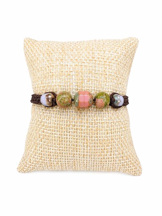 Un bracelet tréssé avecd es pierres naturelles et des perles en verre sur un coussin beige .D'Ici et de Claire