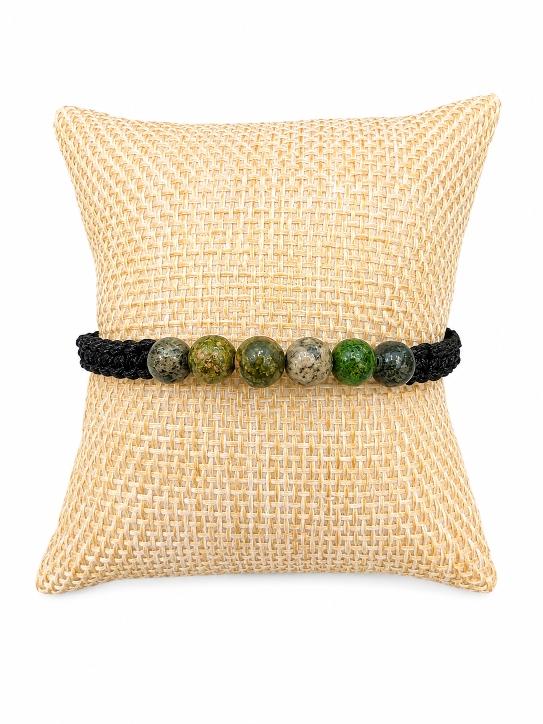 Bracelet tréssé type shamballa avec des perles en pierres naturelles , posé sur un coussin beige .D'Ici et de Claire 