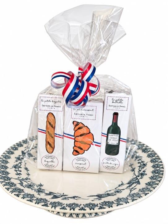 un sachet transparet dans lequel il y a trois savons en forme de croissant , baguette et bouteille de vin 
