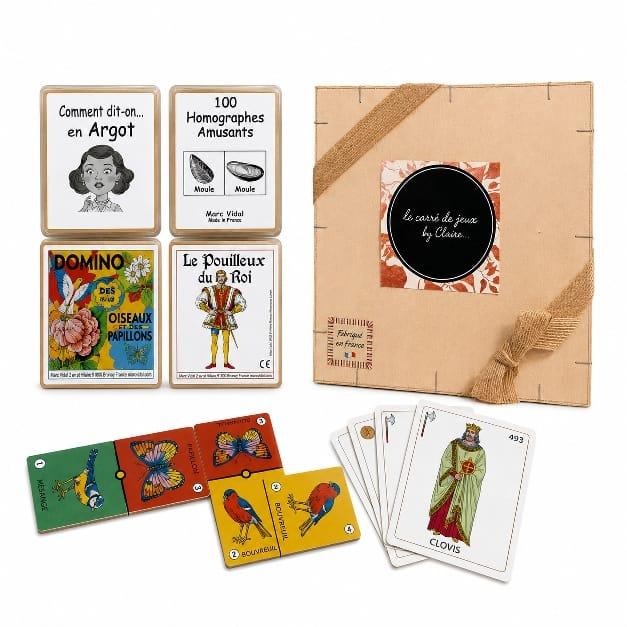 Coffret en bois avec l'inscription "carré de jeu by claire " , plusieurs jeux et plusieurs cartes posées .D'Ici et de claire 