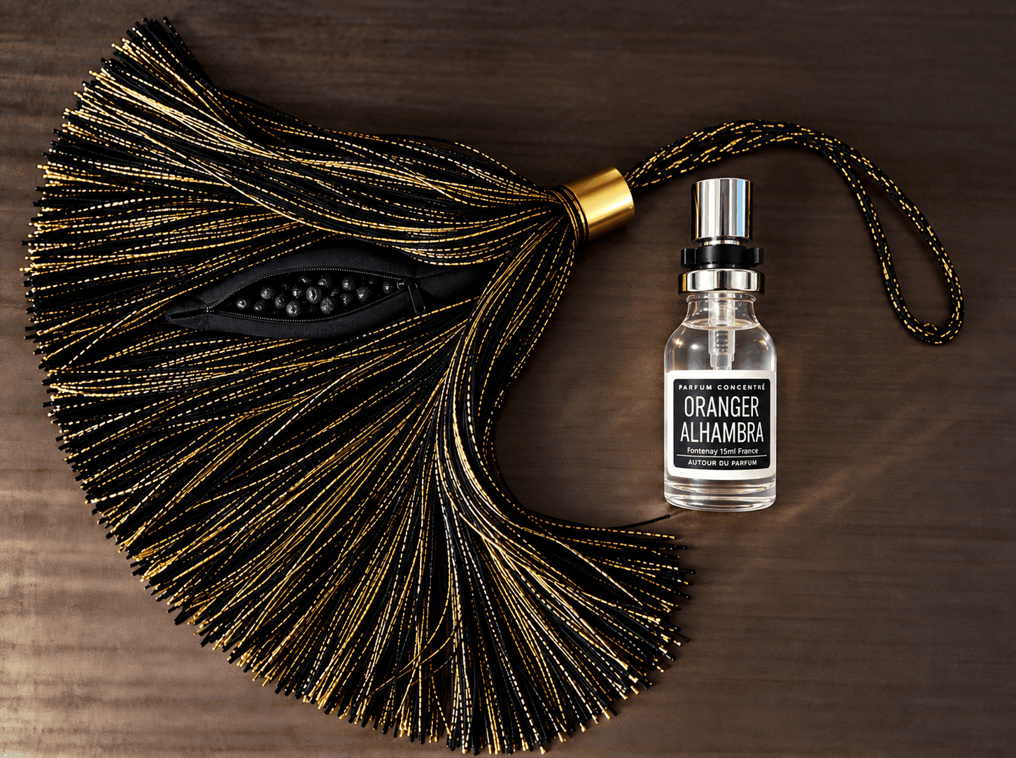 un pompon noir et doré avec des pierres de lave et un flacon ornager alhambra autour du parfum