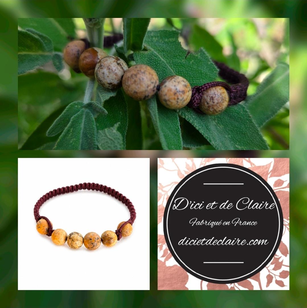 Bracelet tréssé partiellement avec des perles en pierres naturelles de Jaspe Fossile posé dans la verdure avec logo D'Ici et de Claire 